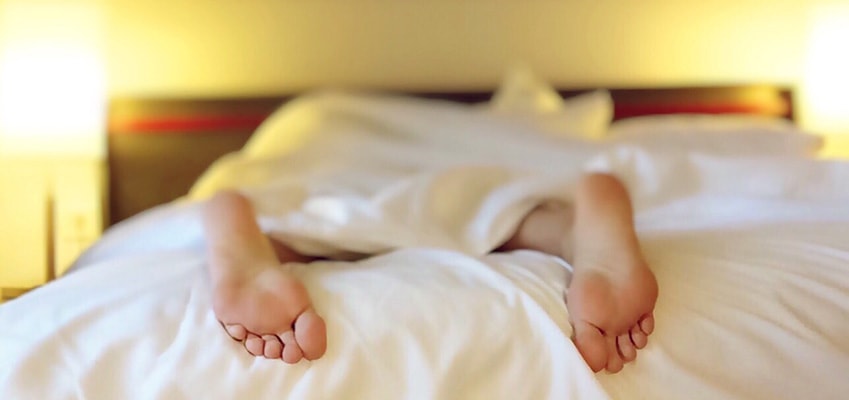 man laying in bed with feet showing